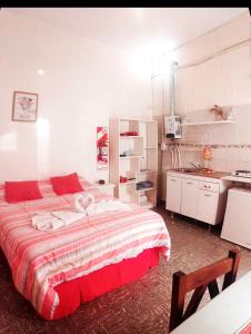 a bedroom with a large bed and a kitchen at Zafiro Departamentos in Capilla del Monte