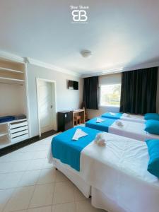 a hotel room with two beds with blue sheets at Bene Beach - Pousada Guarujá in Guarujá +107 photos