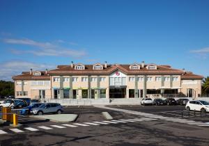 un gran edificio con coches estacionados en un estacionamiento en Hotel Arias Aeropuerto en Monte