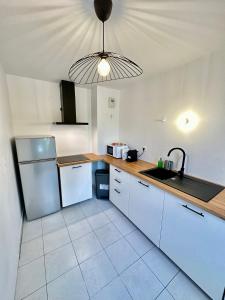 d'une cuisine avec des placards blancs, un réfrigérateur et une lampe. dans l'établissement Magnifique apartment in Paris / Bagnolet 101, à Bagnolet