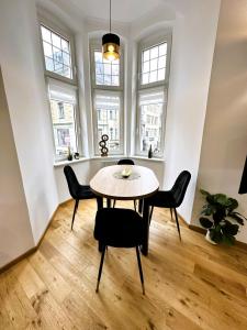 a dining room with a table and chairs and windows at Apartamenty Dream Place in Toruń