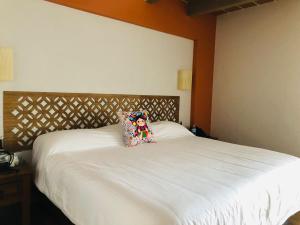 Una cama blanca con una almohada encima. en Hotel La Mansión, en San José Iturbide