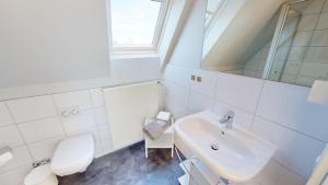 ein weißes Bad mit einem WC und einem Waschbecken in der Unterkunft GAST-ZEIT Kliff 3 in Grömitz