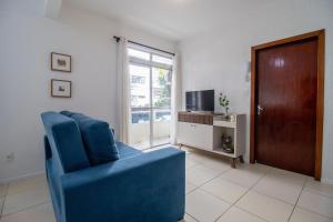 ein Wohnzimmer mit einem blauen Sessel und einem Fernseher in der Unterkunft JOA21 - 2 Dorm, Climatizado, Wi-Fi, Garagem in Balneário Camboriú