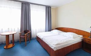 a bedroom with a bed and a table and a chair at Amore Mio Stare Miasto Apartamenty in Elblag