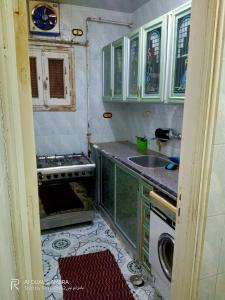 Shaṭṭ `Ezbet el-Laḥm的住宿－شقة مفروشة للايجار ٩٠ م，厨房配有绿色橱柜、水槽和炉灶。