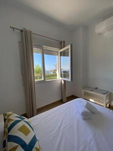 a white bedroom with a bed and a window at Sea Escape 2 in Almuñécar