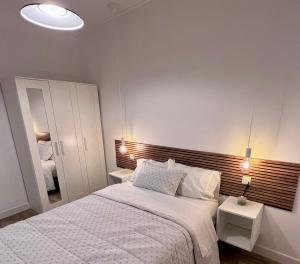 a bedroom with a large white bed with two tables at Soñar en la Plaza Cervantes 2 in Alcalá de Henares