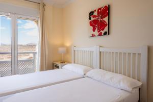 1 dormitorio con cama blanca y ventana en Villas y Apartamentos El Sultan, en Corralejo