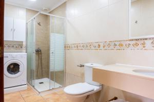 a bathroom with a toilet and a sink and a washing machine at Villas y Apartamentos El Sultan in Corralejo