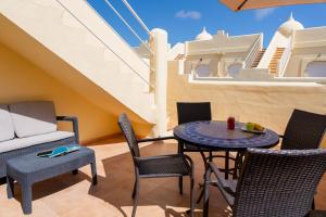 un patio con mesa, sillas y sofá en Villas y Apartamentos El Sultan, en Corralejo