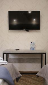einen TV an der Wand mit zwei Wasserflaschen auf dem Tisch in der Unterkunft Gallery Elit Hotel in Dunaivtsi