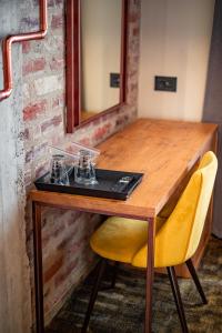 Mustang Boutique Rooms في أوراديا: طاولة خشبية مع مرآة وكرسي اصفر