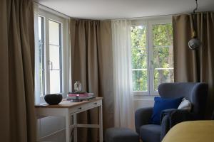 um quarto com duas janelas, uma mesa e uma cadeira em Bergnestli em Oberegg