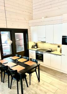 cocina con mesa, sillas y armarios blancos en Sointuilevi 9 Q 65 by Aavalevi Holidays, en Levi
