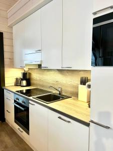 Una cocina con gabinetes blancos y un fregadero. en Sointuilevi 9 Q 65 by Aavalevi Holidays, en Levi
