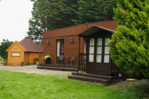 uma pequena cabana com um alpendre num quintal em The Cabin at Ashleigh House em Gaerwen