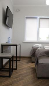Schlafzimmer mit einem Bett und einem Schreibtisch mit einem TV in der Unterkunft Gallery Elit Hotel in Dunaivtsi