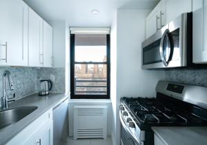 La cuisine est équipée de placards blancs et d'un four avec plaques de cuisson. dans l'établissement Excellent 3 Bed 1 Bath In Mid East, à New York