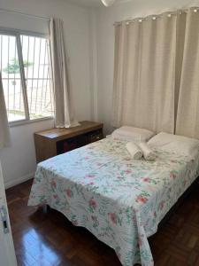 Un dormitorio con una cama con una manta de flores y una ventana en Aloha aluguel para temporadas en Vitória