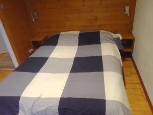 a bed with a black and white checkered blanket at Appt Ponteil in Les Deux Alpes