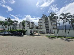 a parking lot with palm trees in front of a building at Apto em frente à praia em Caraguatatuba in Caraguatatuba