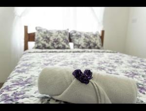 Una cama con una toalla con una flor morada. en Residencia las brisas Griegas, en Quepos