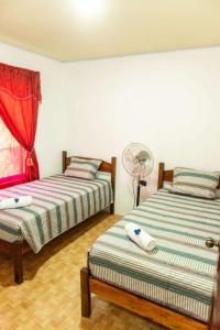 two beds in a room with a fan at Residencia las brisas Griegas in Quepos