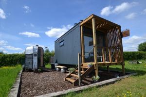 a tiny house and a trailer in a yard at Twin Barn Shepherd’s Huts in Norwich