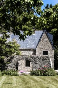 una casa de piedra con flores en un patio en Le Manoir de Menglieu, en Treffléan