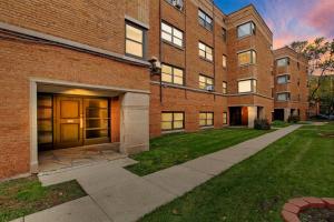 a brick building with a door and a grass yard at 2BR Roomy & Stylish Apartment in Rogers Park - Sheridan N2 in Chicago