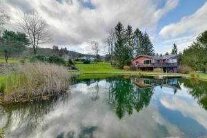 a house next to a lake with a house at Spacious Finger Lakes Home with Mountain Views 