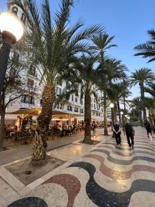 una calle con palmeras y gente caminando por una acera en Hostal Milan, en Alicante