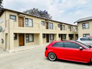 un'auto rossa parcheggiata di fronte a un edificio di Royal Mansion Lodge a Johannesburg