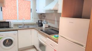 eine kleine Küche mit Spüle, Waschmaschine und Trockner in der Unterkunft Apartamentos varios con 2 dorm en Marina Dor , la playa de Amplaries , vista lateral al mar in Oropesa del Mar