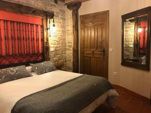 1 dormitorio con 1 cama y puerta de madera en Casas Rurales Hoces del Duratón, en Carrascal del Río