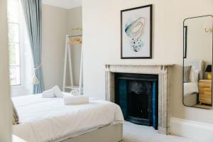 a white bedroom with a bed and a fireplace at Luxury, Central, Sun-Filled 3 Bed Haven in Bath in Bath +16 photos