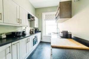 a kitchen with white cabinets and black counter tops at Luxury, Central, Sun-Filled 3 Bed Haven in Bath in Bath