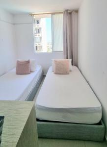 two beds in a room with a window at Amplio y Residencial piso 9 in Cartagena de Indias