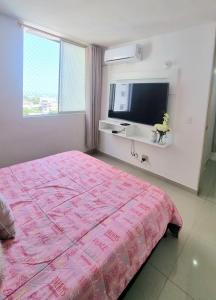 a bedroom with a pink bed and a flat screen tv at Amplio y Residencial piso 9 in Cartagena de Indias