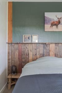 1 cama con cabecero de madera y ciervo en la pared en Huisje Wildzicht, en 't Zand