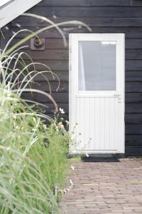 una puerta blanca en el lateral de una casa en Huisje Wildzicht, en 't Zand