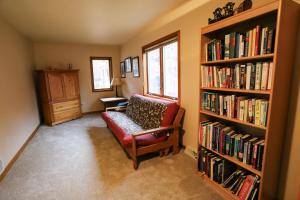 a living room with a red chair and a book shelf with books at LakePlace Bed & Breakfast 