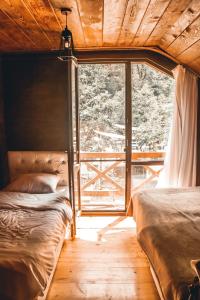 two beds in a room with a large window at Park cottage Mtirala National Park in Ch'ak'vist'avi