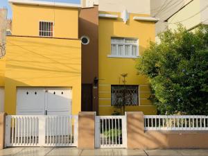 una casa amarilla con dos puertas blancas de garaje en Peruvian House - Miraflores, en Lima