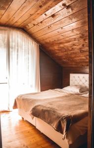 a bed in a bedroom with a wooden ceiling at Park cottage Mtirala National Park in Ch'ak'vist'avi