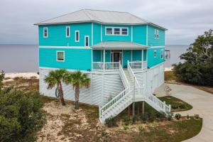 une maison bleue sur la plage avec des escaliers dans l'établissement Ocean Springs Magnolia Beach House on Pvt Beach!, à Ocean Springs
