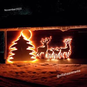 Villa Haaveranta - Cosy cabin by the lake في روفانييمي: ثلاثة غزلان يقفون أمام موقد مع شجرة عيد الميلاد