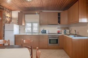 een keuken met houten kasten en een witte koelkast bij Eleni villa in Saktoúria