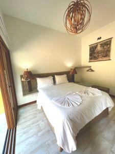 1 dormitorio con 1 cama blanca grande con lámpara de araña en The Madalena Pousada, en Imbassai